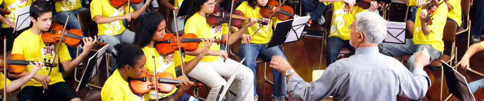 children sitting in orchestra format being governed by a conductor